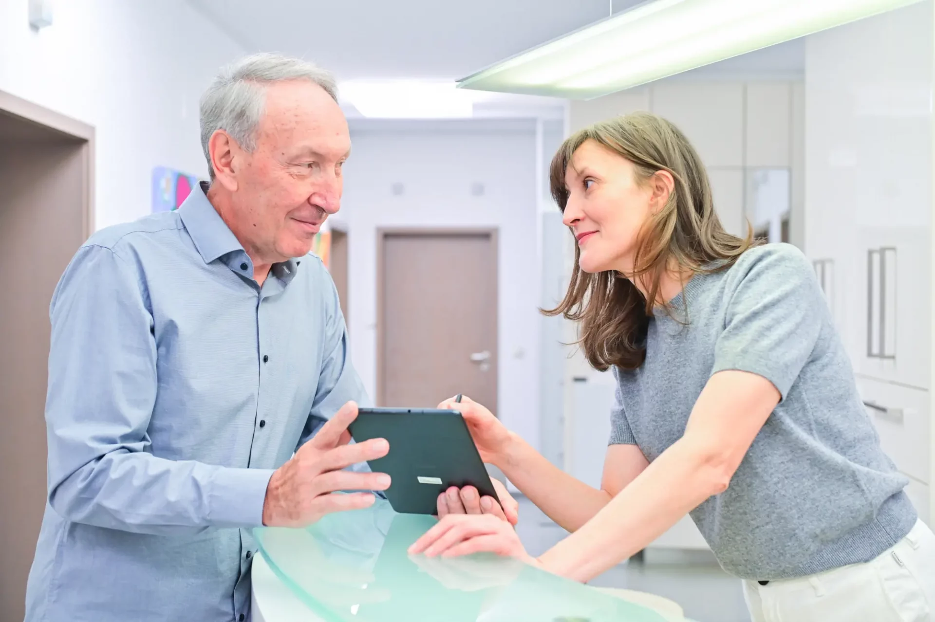 Waldemar Grosch und Dr. Ella Grosch mit einem Tablet an der Empfangstheke